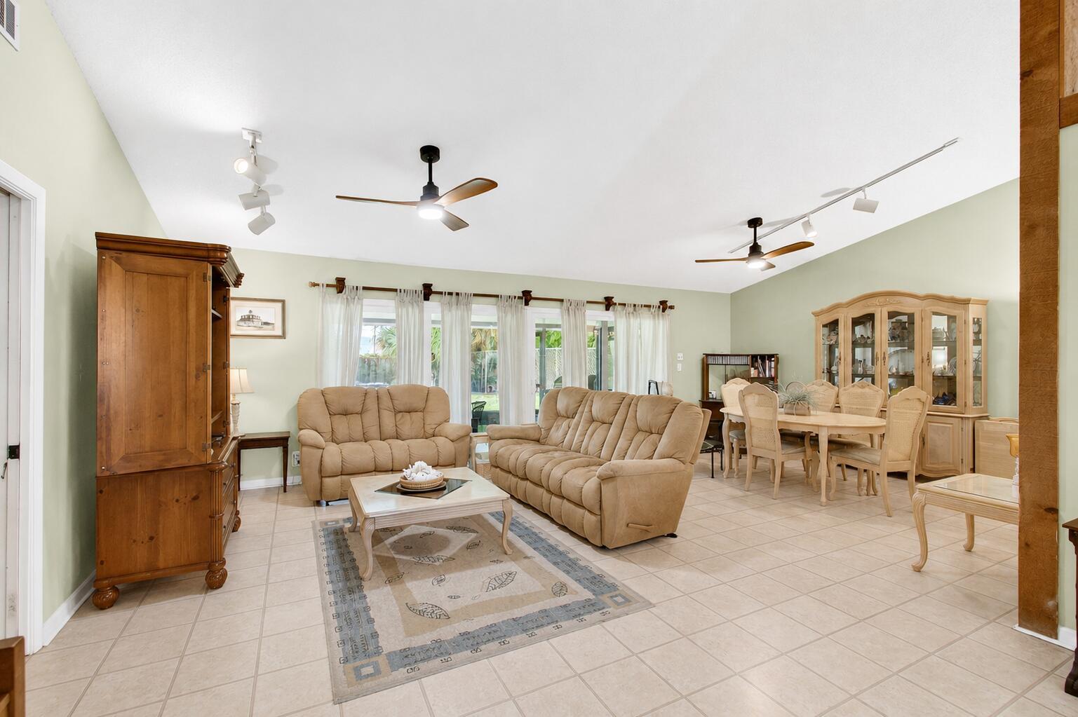 A spacious living and dining room with tile floors, vaulted ceilings, and beige furniture — 2400 SW 19th Avenue, Boynton Beach FL 33426, BOYNTON BEACH, FL