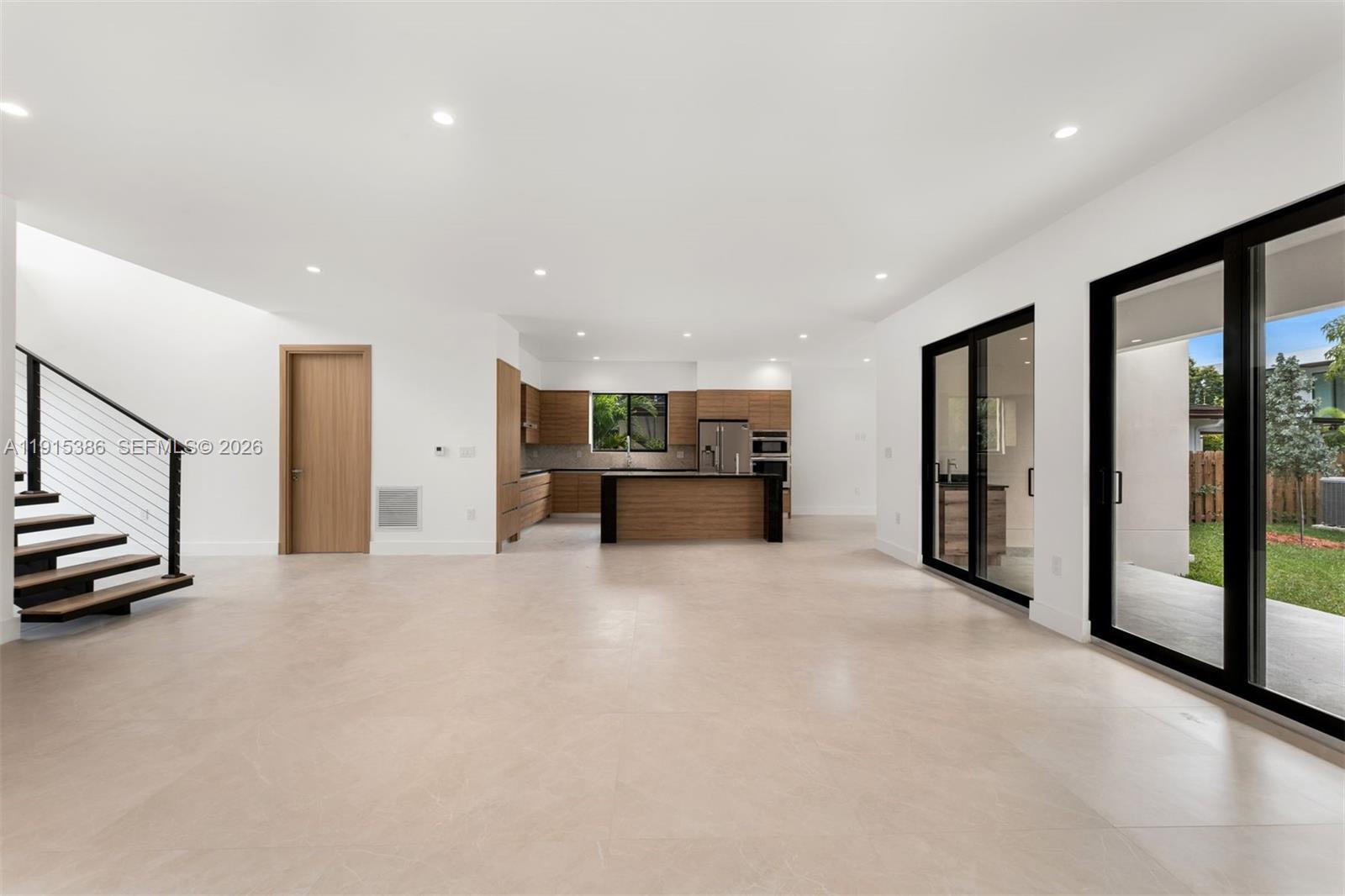 An open-concept living area features a modern kitchen, light tile floors, and large sliding glass doors — 1366 SW 15th St, Miami FL 33145, MIAMI, FL