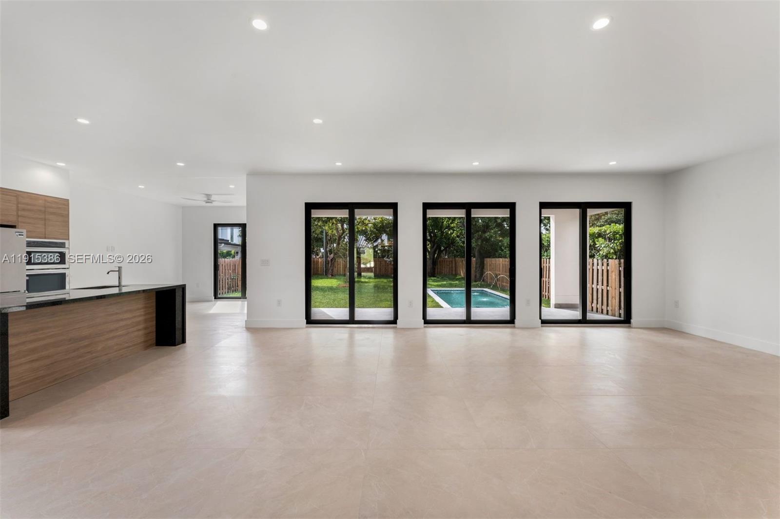 A modern open-concept living area features light tile floors, a kitchen island, and sliding doors — 1366 SW 15th St, Miami FL 33145, MIAMI, FL