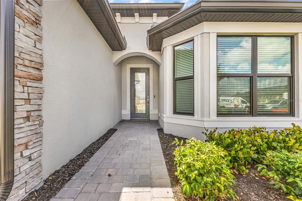 A single-story house with a stone facade, gray garage door, and a paved driveway — 4400 LAKESIDE GROVE PLACE, NORTH PORT, FL