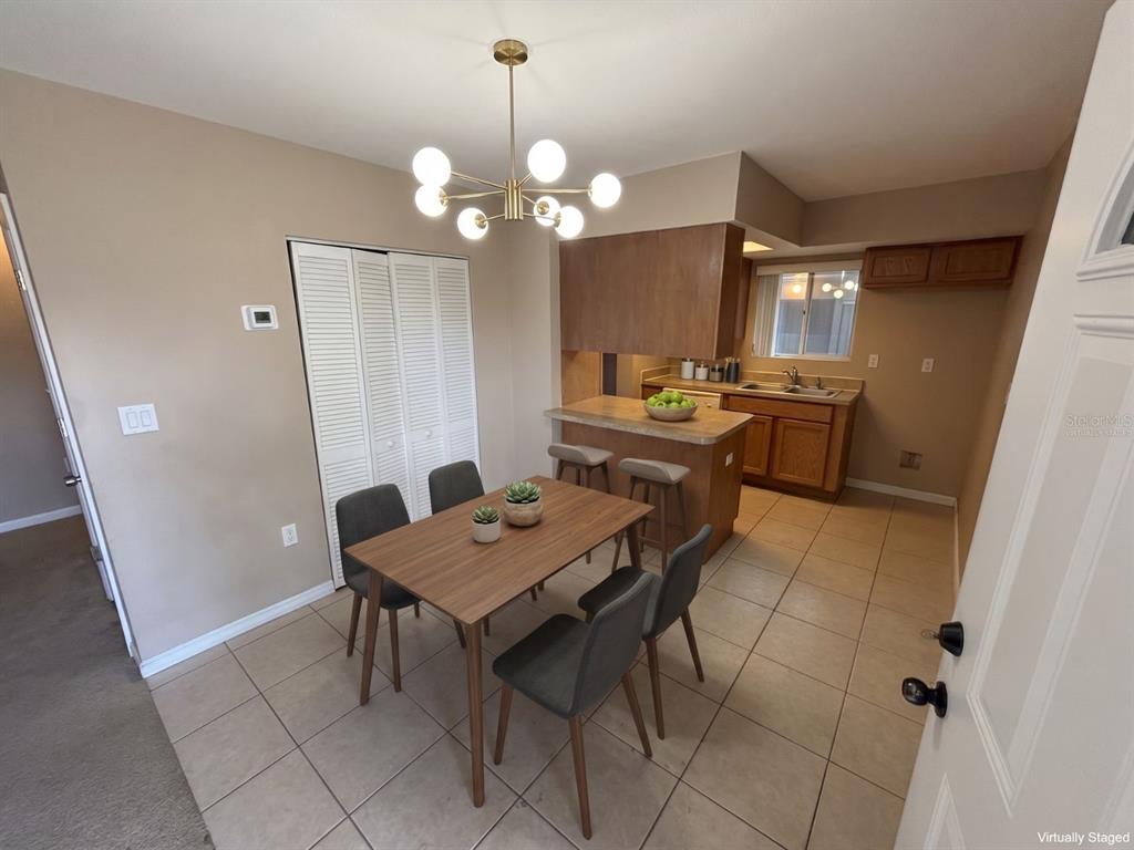 A dining area with a wood table, four chairs, and a kitchen counter with stools — 5568 GREEN SHADOWS PLACE UNIT 21-1, ORLANDO, FL
