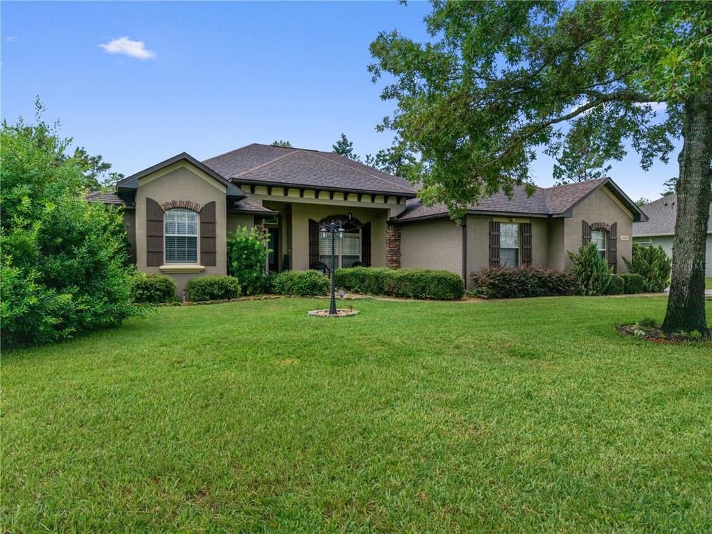 A single-story house with a green stucco exterior, dark shutters, and a large front lawn — 4950 SW 114TH STREET ROAD, OCALA, FL