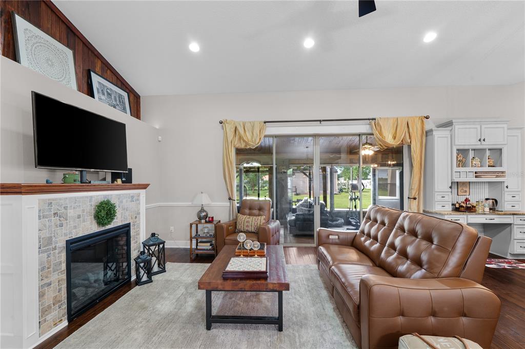 A living room features a stone fireplace, a brown leather sofa, and sliding glass doors — 4950 SW 114TH STREET ROAD, OCALA, FL