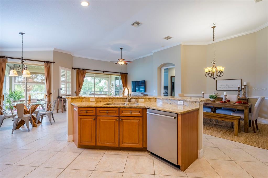 A kitchen island with a stainless steel dishwasher sits in an open-concept dining area — 9453 NE DISCOVERY TERRACE UNIT 201C, BRADENTON, FL