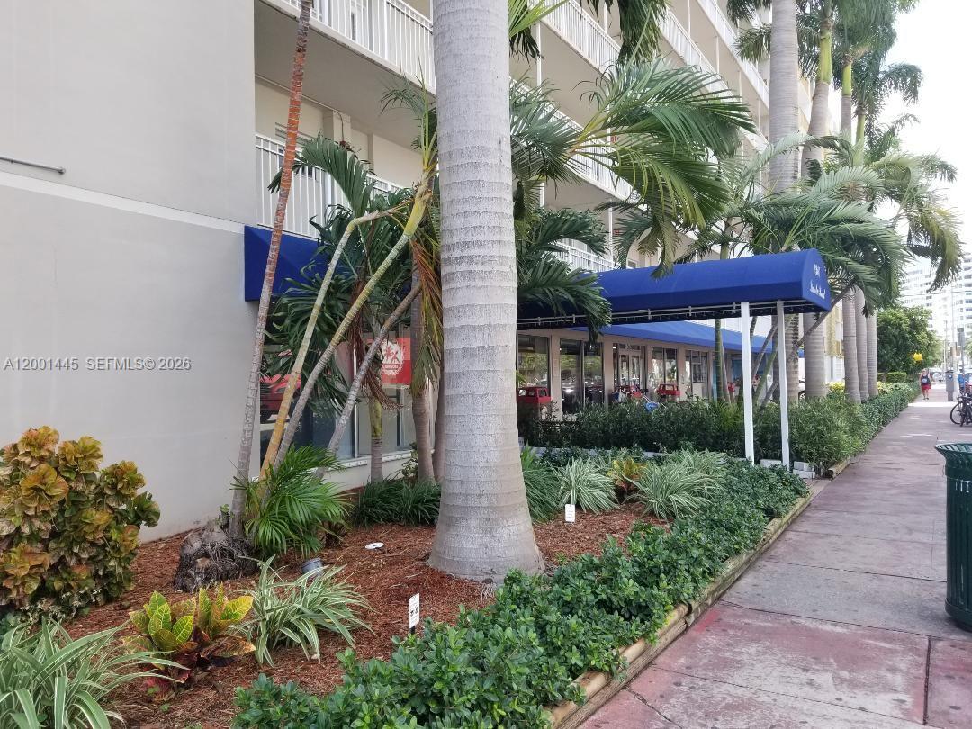 The exterior of a multi-story building features a blue awning, palm trees, and landscaping — 1300 Lincoln Rd # A301, Miami Beach FL 33139, MIAMI BEACH, FL