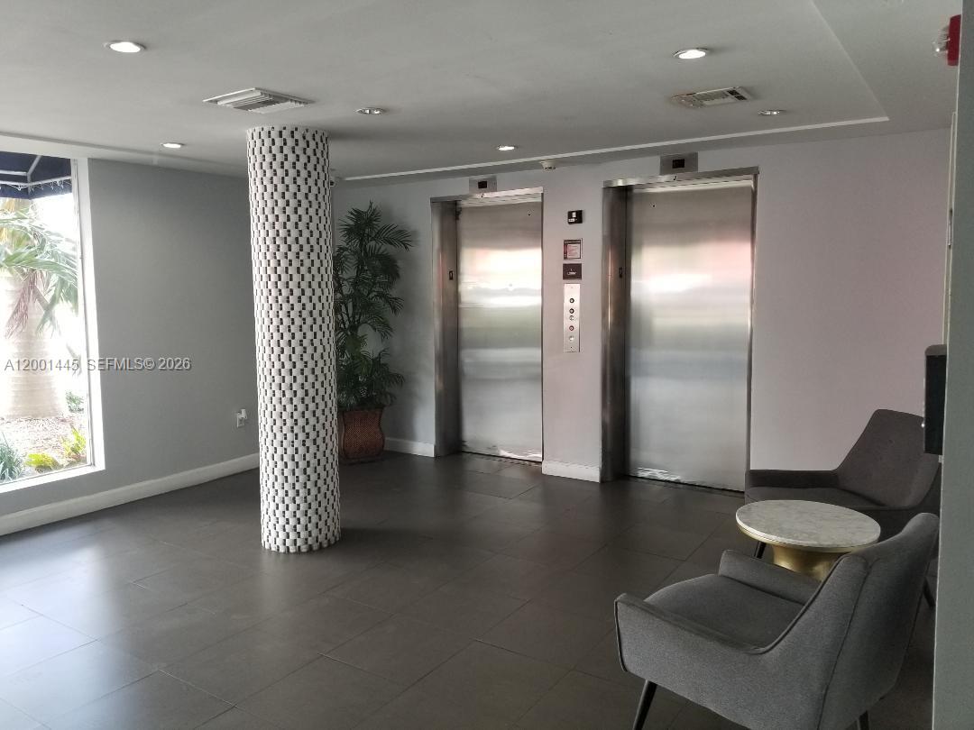 A lobby area features two stainless steel elevators, a tiled pillar, and gray armchairs — 1300 Lincoln Rd # A301, Miami Beach FL 33139, MIAMI BEACH, FL