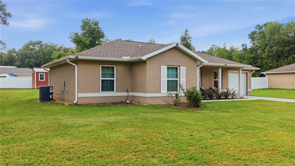 A tan, single-story house with a shingled roof, white trim, and a grassy front yard — 14055 SE 43RD TERRACE, SUMMERFIELD, FL