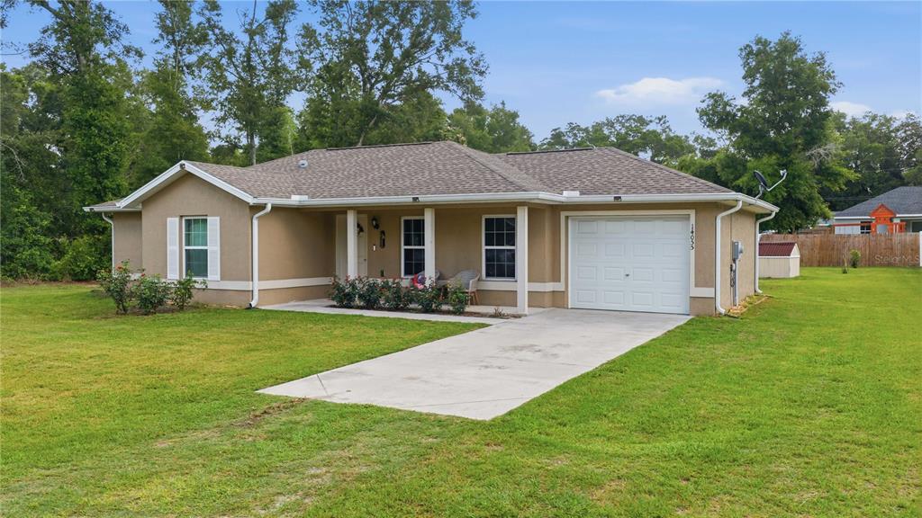A single-story tan house with a white garage door and a concrete driveway — 14055 SE 43RD TERRACE, SUMMERFIELD, FL