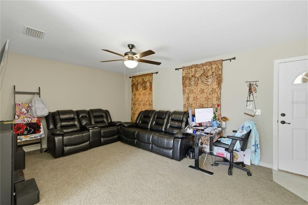 A living room features beige carpet, black leather sofas, a desk, and a ceiling fan — 14055 SE 43RD TERRACE, SUMMERFIELD, FL