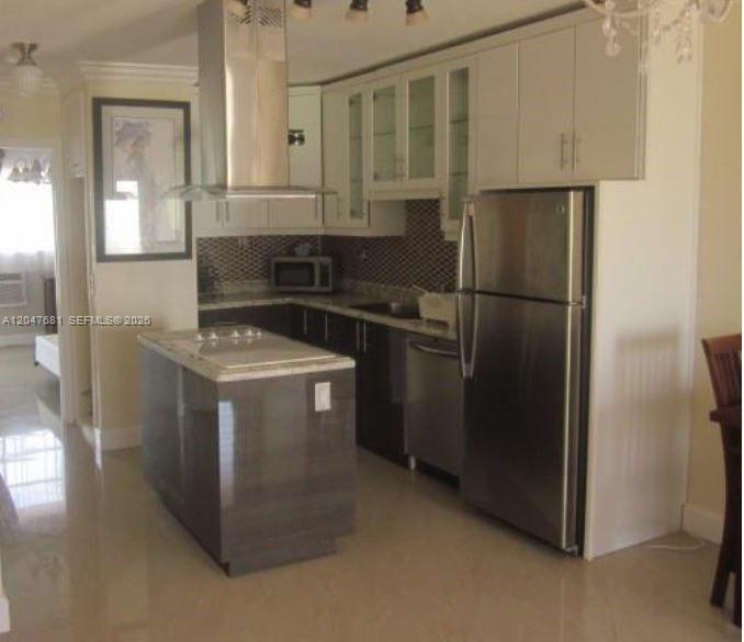 A kitchen features a central island, stainless steel appliances, and white upper cabinetry — 600 Layne Blvd # 115, Hallandale Beach FL 33009, HALLANDALE BEACH, FL