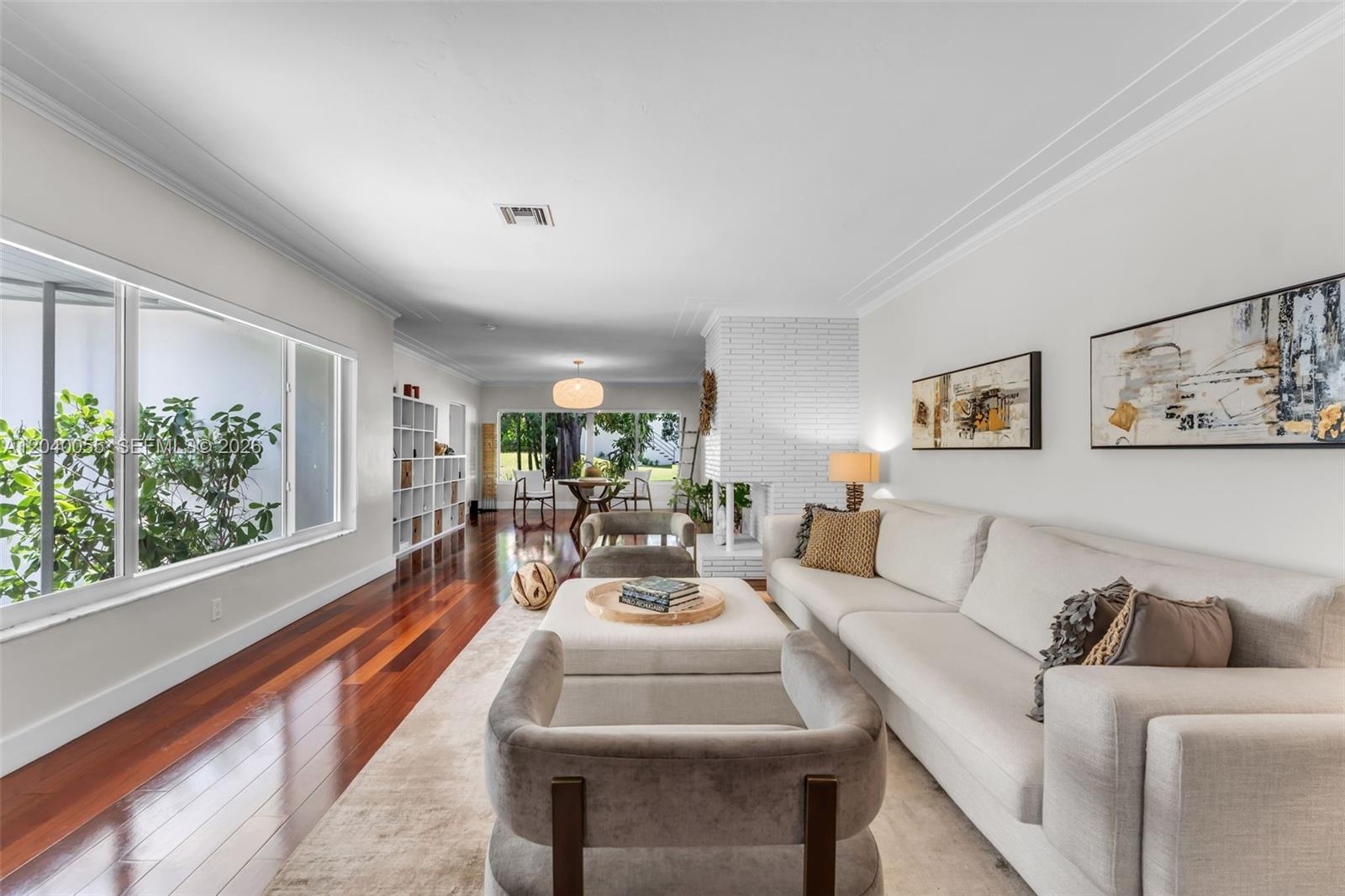 A living room features hardwood floors, a white brick fireplace, and a light-colored sectional sofa — 8 Pinta Rd, Miami FL 33133, MIAMI, FL