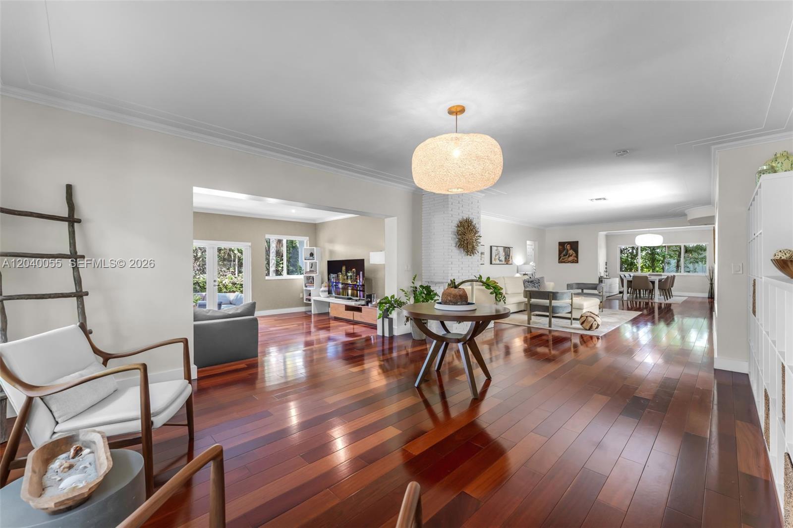 A bright living room features hardwood floors, a white brick fireplace, and a large sectional sofa — 8 Pinta Rd, Miami FL 33133, MIAMI, FL