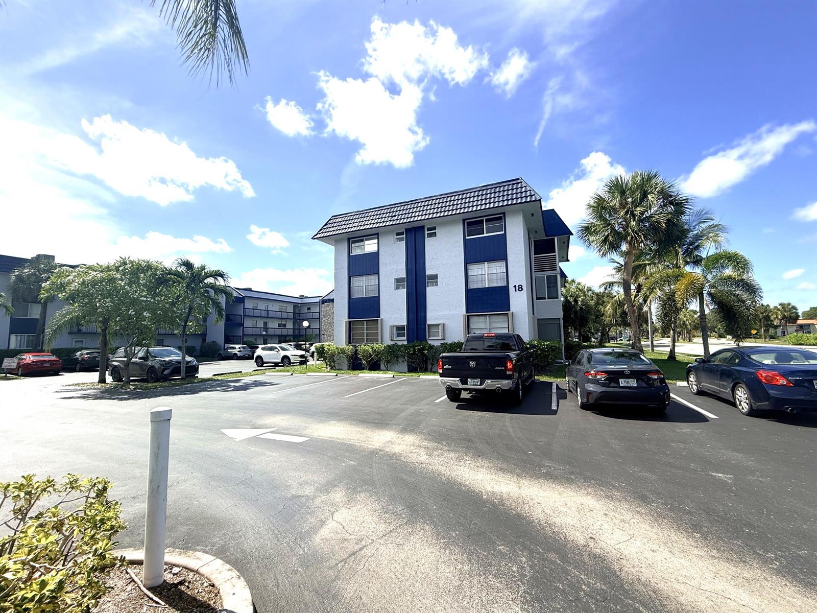 A three-story apartment building with blue and white exterior walls stands in a parking lot — 3050 Holiday Springs Boulevard # 111, Margate FL 33063, MARGATE, FL