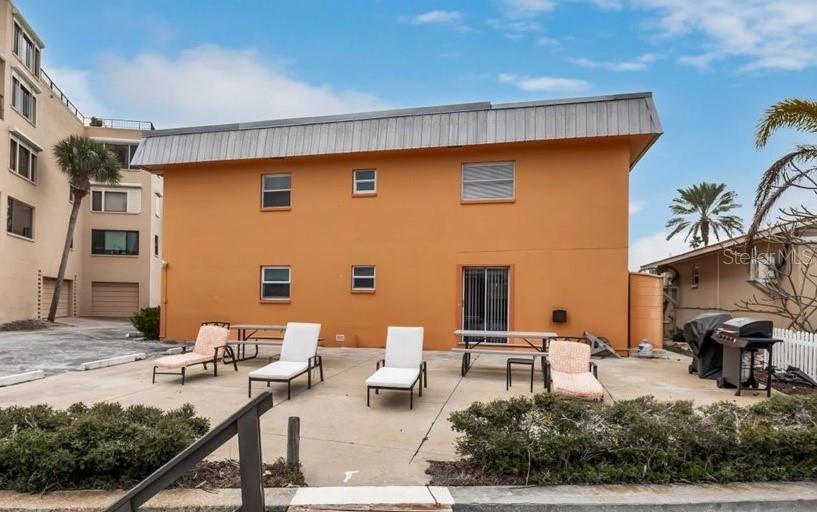 The exterior of a two-story orange building features a concrete patio with lounge chairs — 18205 GULF BOULEVARD, REDINGTON SHORES, FL