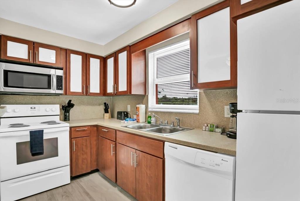 A kitchen features wood cabinets, white appliances, a double sink, and a window with blinds — 18205 GULF BOULEVARD, REDINGTON SHORES, FL