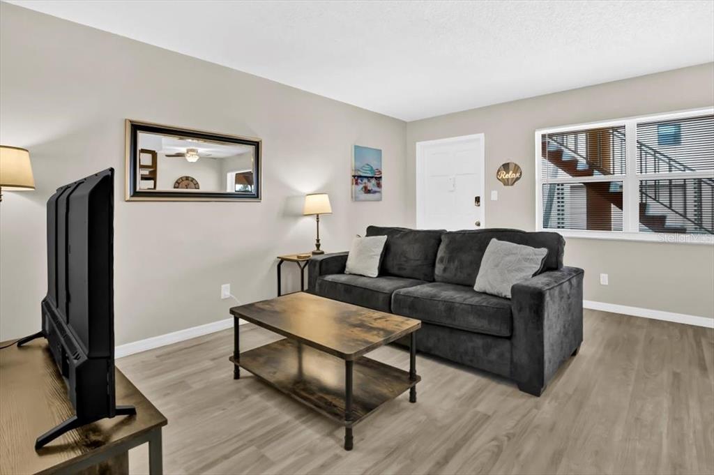 A living room features a dark sofa, a wooden coffee table, and light wood-look flooring — 18205 GULF BOULEVARD, REDINGTON SHORES, FL
