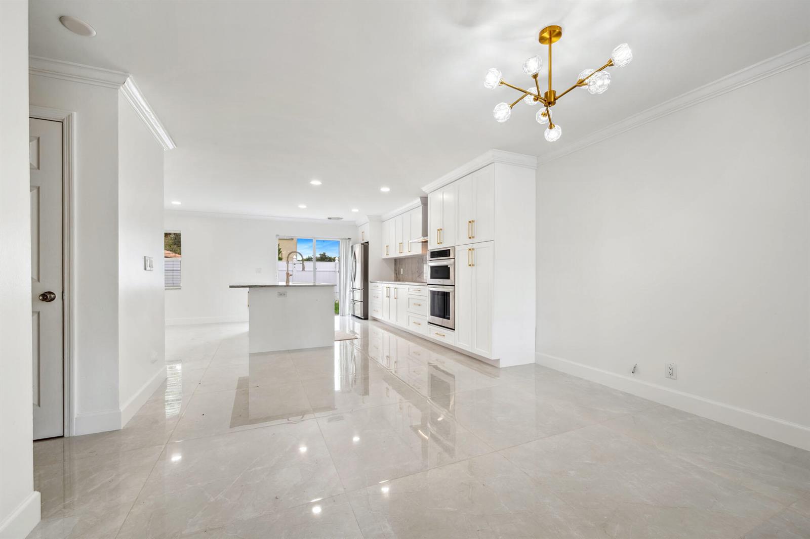 A bright kitchen features white cabinetry, gold hardware, a center island, and polished tile floors — 3460 Commodore Court, West Palm Beach FL 33411, WEST PALM BEACH, FL