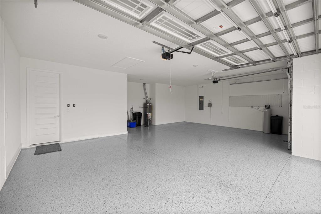 A spacious, empty garage with white walls, a gray epoxy floor, and a metal ceiling — 8418 SW 93RD CIRCLE, OCALA, FL