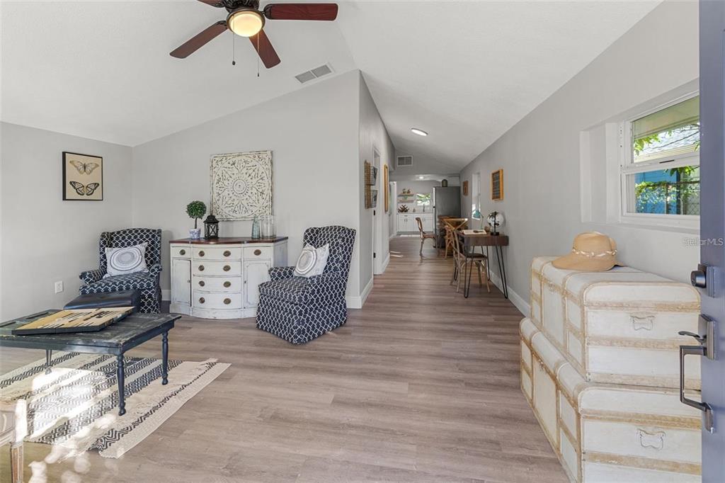A living area with light wood floors, two patterned armchairs, and a white dresser — 1606 E OSBORNE AVENUE, TAMPA, FL