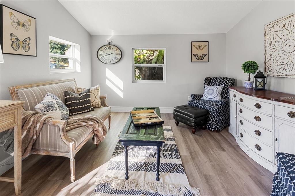 A living room features a striped settee, a patterned armchair, a coffee table, and wall art — 1606 E OSBORNE AVENUE, TAMPA, FL