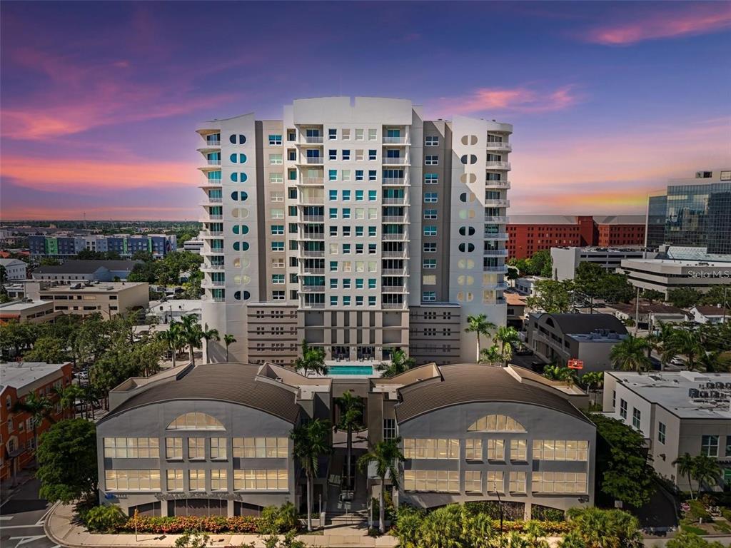 An aerial view shows a tall residential building with a pool and low-rise commercial structures — 1771 RINGLING BOULEVARD UNIT 603, SARASOTA, FL