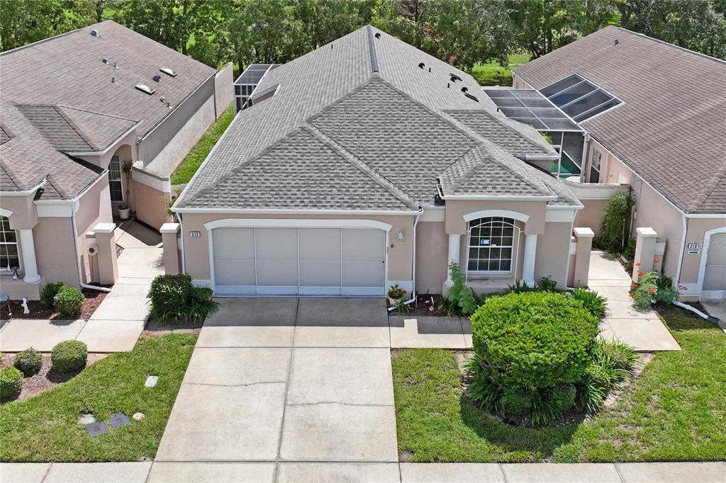 An aerial view shows the exterior of a tan suburban house with a gray roof — 312 ROYAL PALM WAY, SPRING HILL, FL