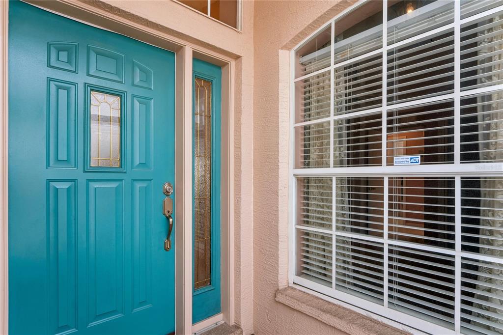 A teal front door with a side light window sits next to a white-framed window — 312 ROYAL PALM WAY, SPRING HILL, FL