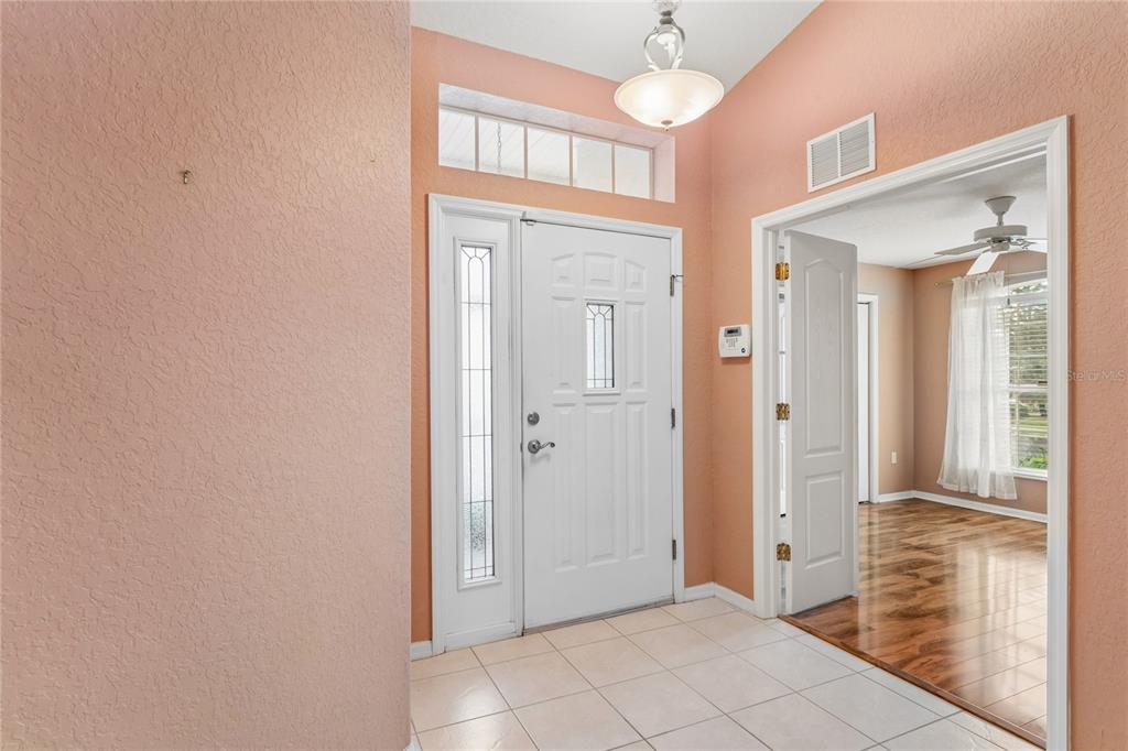 An entryway features peach walls, white trim, a tiled floor, and a white front door — 312 ROYAL PALM WAY, SPRING HILL, FL