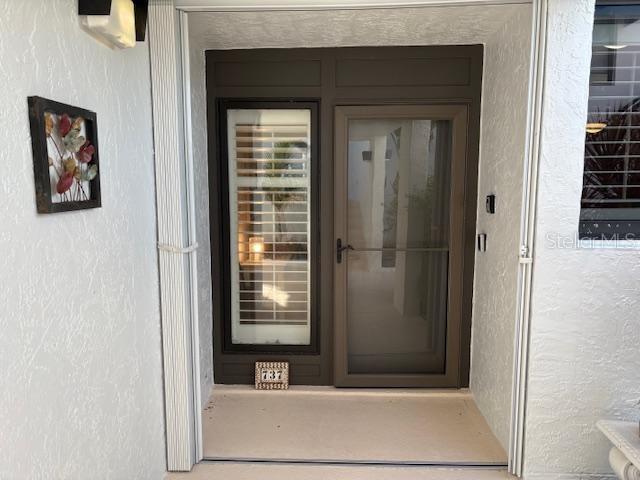 A front entryway features a glass storm door, a window with shutters, and a wall plaque — 737 BAYPORT WAY UNIT D, LONGBOAT KEY, FL