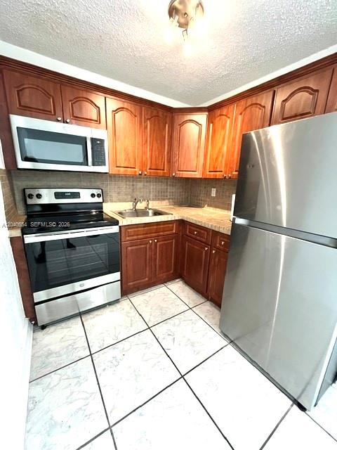 A kitchen features wood cabinets, stainless steel appliances, and white tiled flooring — 444 SW 4th St # 404, Miami FL 33130, MIAMI, FL