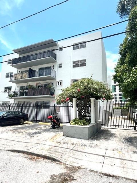 A multi-story white apartment building features balconies with black railings and a gated parking area — 444 SW 4th St # 404, Miami FL 33130, MIAMI, FL