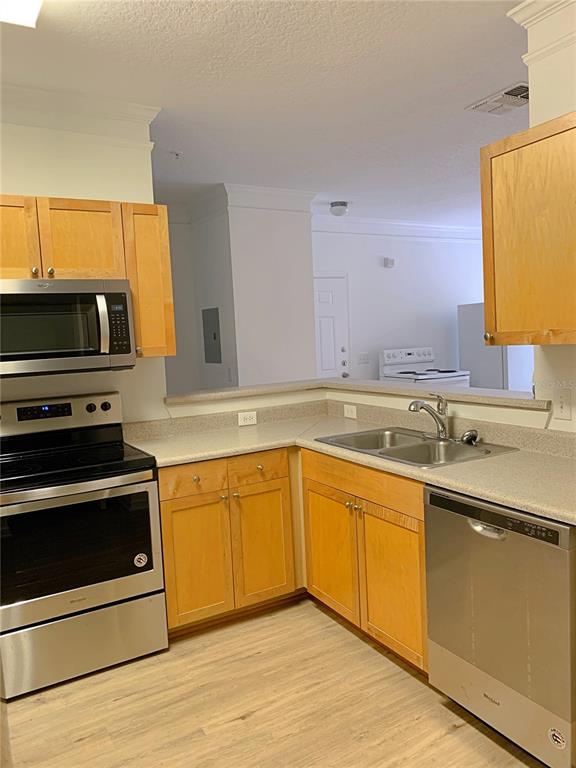 A kitchen features light wood cabinets, stainless steel appliances, and a double-basin sink — 8848 VILLA VIEW CIRCLE UNIT 203, ORLANDO, FL