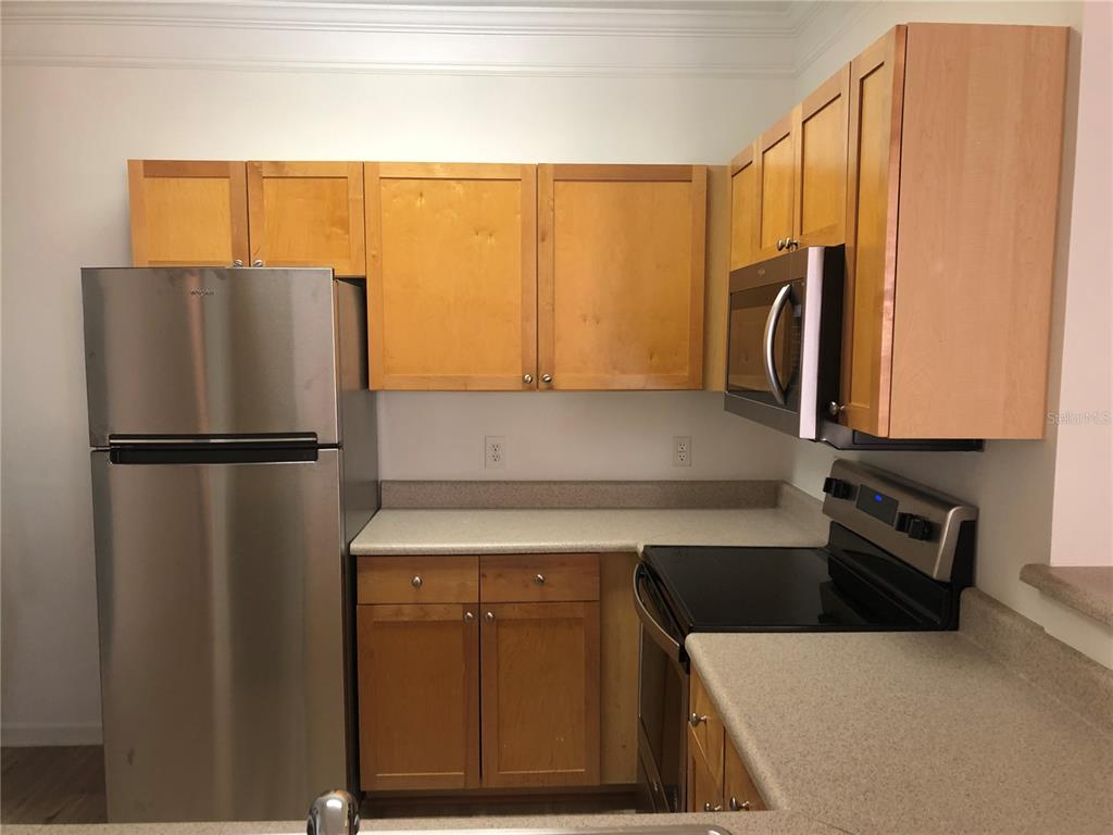 A kitchen featuring light wood cabinets, stainless steel appliances, and beige laminate countertops — 8848 VILLA VIEW CIRCLE UNIT 203, ORLANDO, FL
