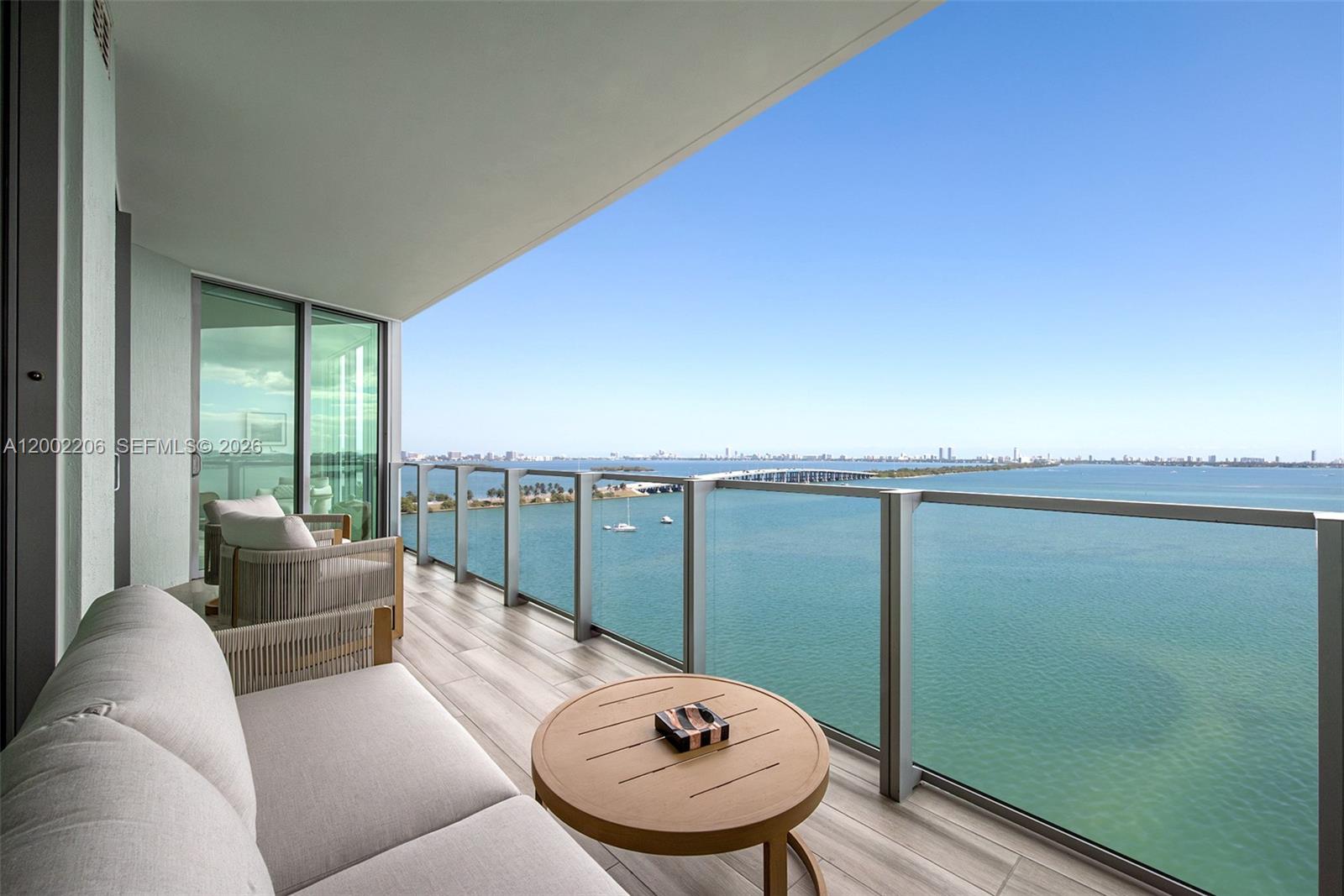 A balcony with outdoor seating overlooks a bay with a bridge and city skyline — 2900 NE 7th Ave # 1505, Miami FL 33137, MIAMI, FL
