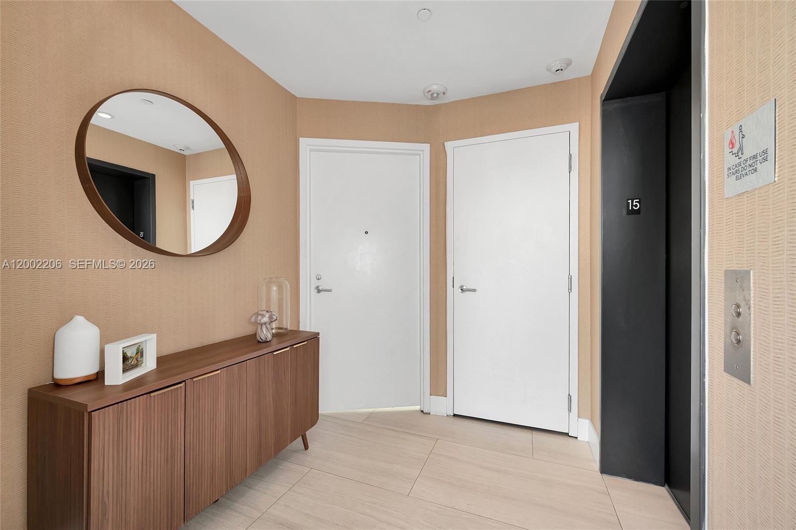 A hallway features a wooden console table, a round mirror, two white doors, and an elevator — 2900 NE 7th Ave # 1505, Miami FL 33137, MIAMI, FL