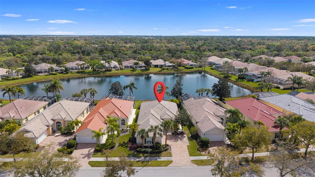 An aerial view shows a suburban neighborhood with houses bordering a lake — 7687 ULIVA WAY, SARASOTA, FL