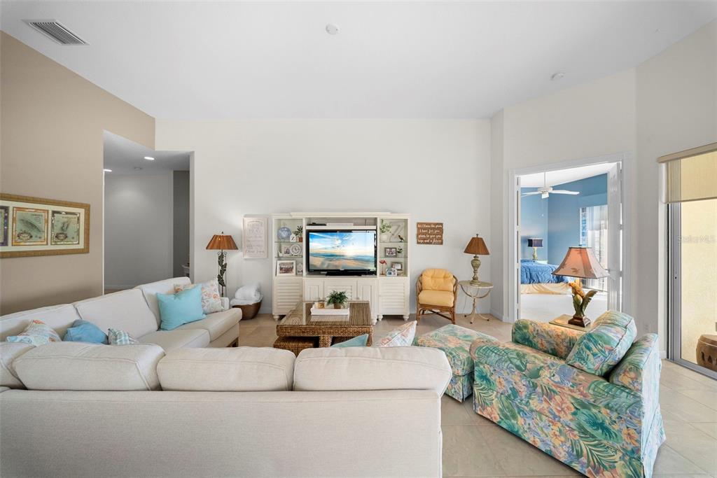 A living room features a white entertainment center, a beige sectional, and a floral armchair — 7687 ULIVA WAY, SARASOTA, FL