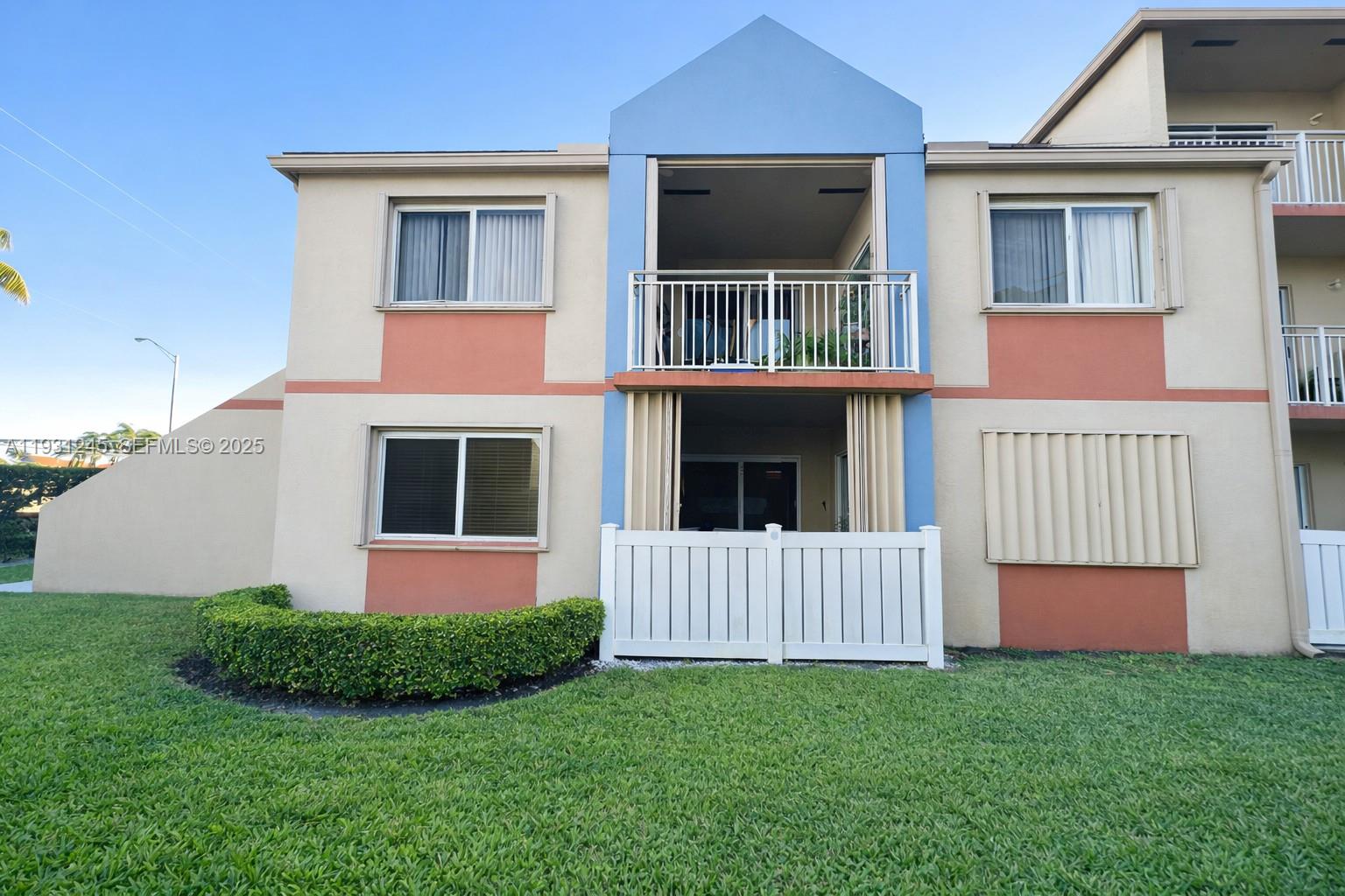 A two-story apartment building exterior features a blue central section with balconies and tan walls — 18810 NW 57th Ave # 102, Hialeah FL 33015, HIALEAH, FL