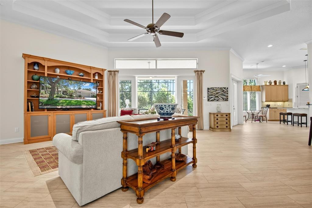 A living room with a tray ceiling, wood entertainment center, and an open kitchen beyond — 10 S WATERVIEW DRIVE, PALM COAST, FL