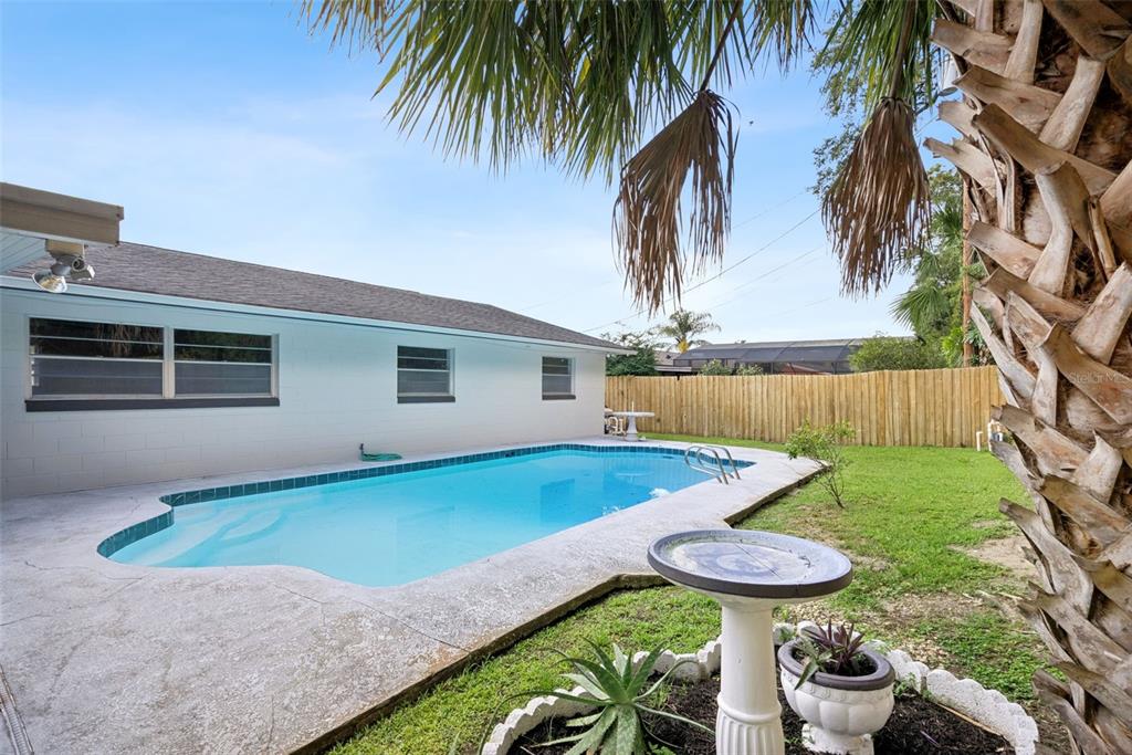 A backyard features a rectangular swimming pool, a concrete patio, and a wooden privacy fence — 2713 YUCCA STREET, ORLANDO, FL