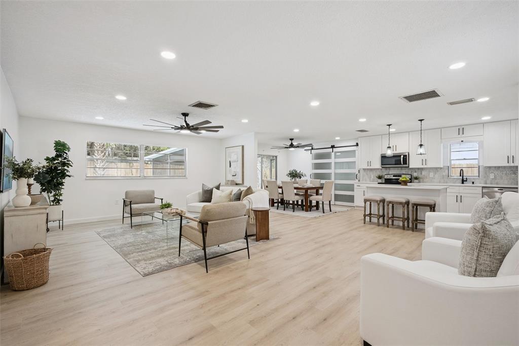 An open-concept living and dining area features light wood flooring, white cabinetry, and recessed lighting — 2713 YUCCA STREET, ORLANDO, FL