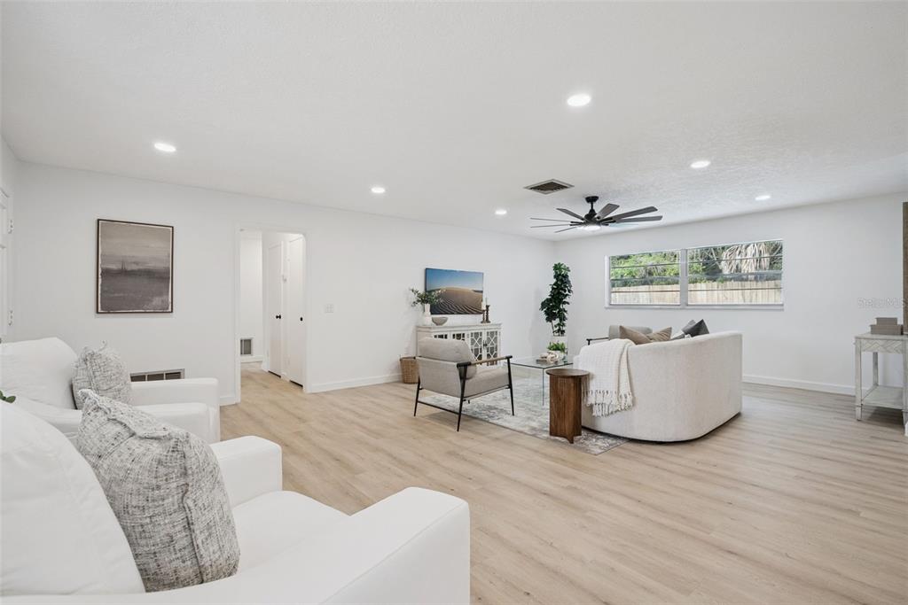 A bright living room features white walls, light wood flooring, and modern neutral furniture — 2713 YUCCA STREET, ORLANDO, FL