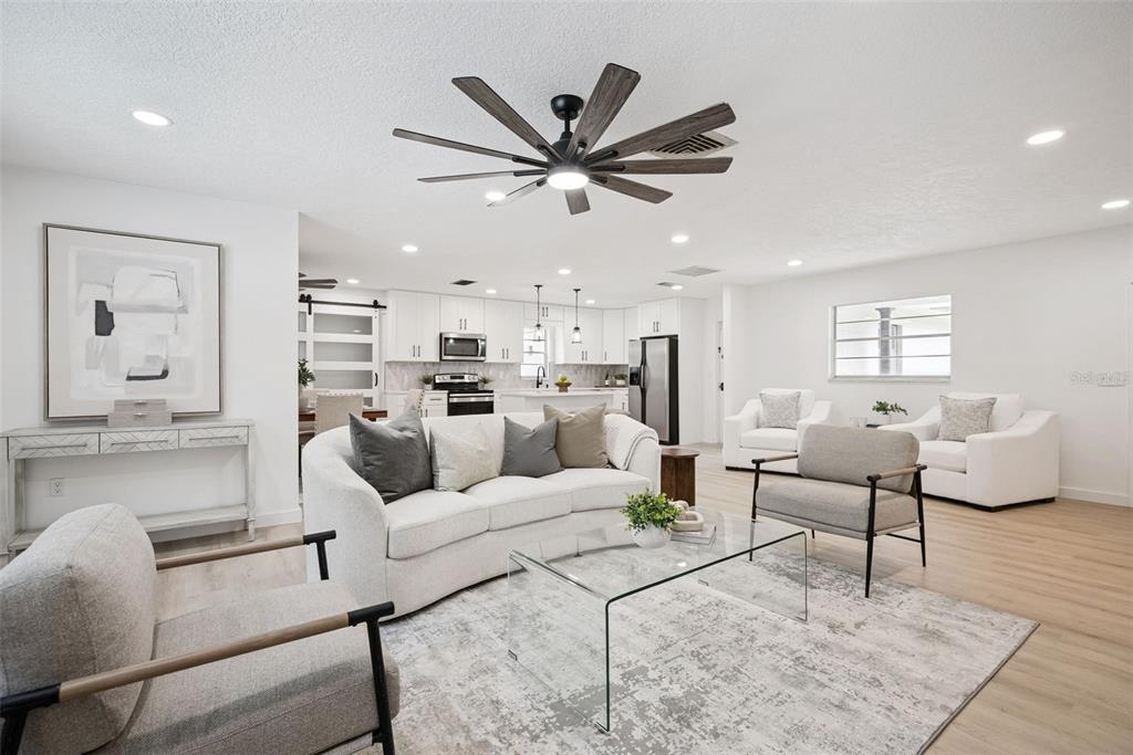 A bright, open-concept living room and kitchen featuring light wood flooring and modern furniture — 2713 YUCCA STREET, ORLANDO, FL