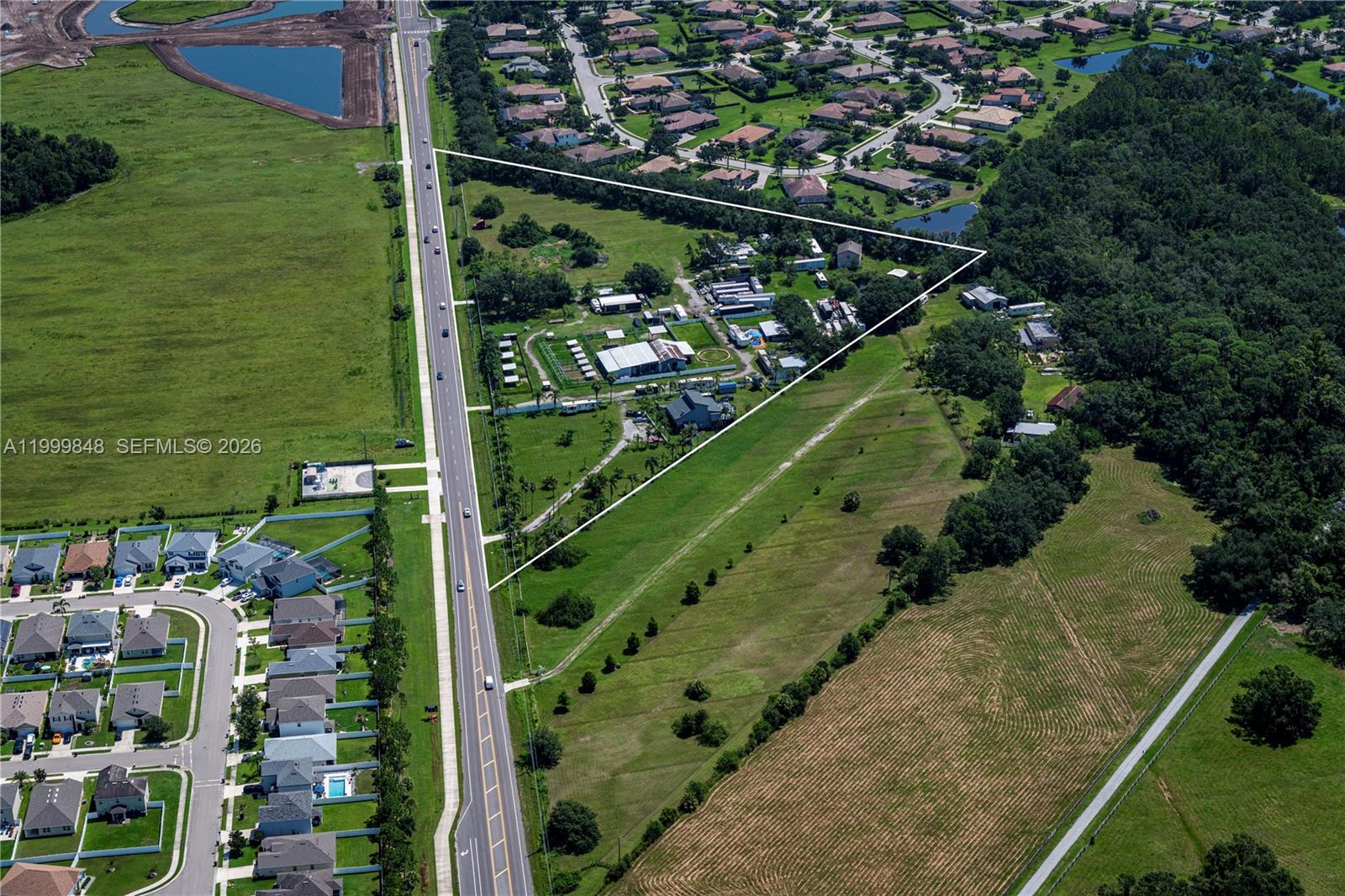 An aerial view shows a triangular plot of land bordered by a road and trees — 211 Rye Rd NE, Bradenton FL 34212, BRADENTON, FL