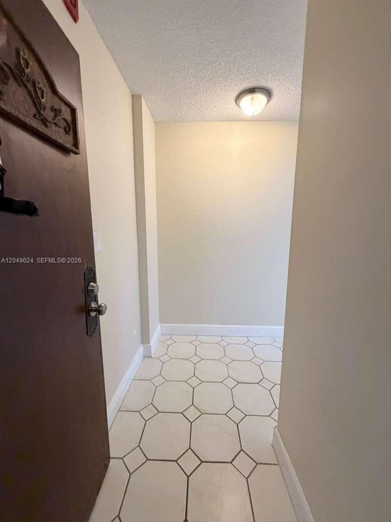 A small entryway features light-colored tile flooring, beige walls, and a ceiling-mounted light fixture — 3720 Inverrary Dr # 3L, Lauderhill FL 33319, LAUDERHILL, FL