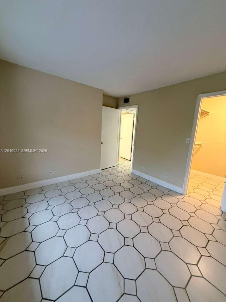 An empty room features light-colored walls and white tile flooring with a geometric pattern — 3720 Inverrary Dr # 3L, Lauderhill FL 33319, LAUDERHILL, FL