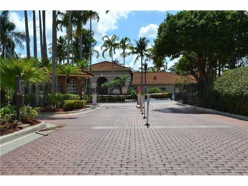 A gated entrance with a brick-paved driveway leads to a building with a tile roof — 18352 NW 68th Avenue # H, Hialeah FL 33015, HIALEAH, FL