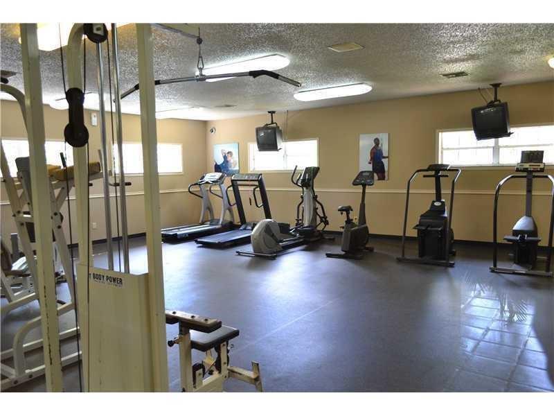 A gym room features various exercise machines, including treadmills, stationary bikes, and a cable machine — 18352 NW 68th Avenue # H, Hialeah FL 33015, HIALEAH, FL