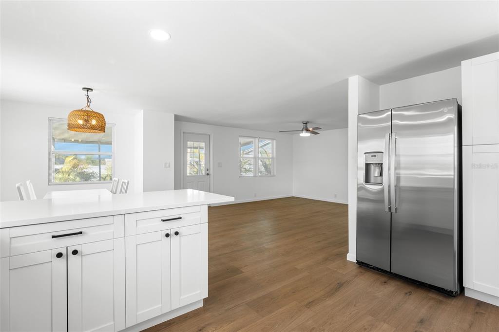 A kitchen with white cabinets and a stainless steel refrigerator opens into a living area — 7271 MOUNT ARLINGTON DRIVE NE UNIT 430, ST PETERSBURG, FL