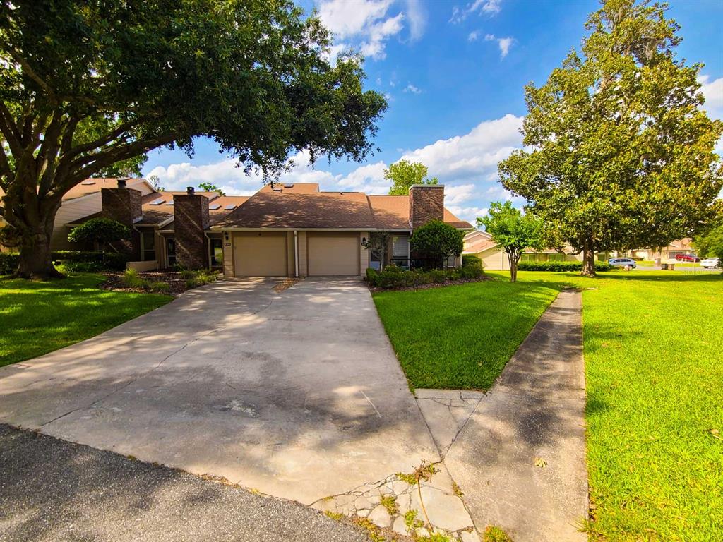 A duplex with two garages, brick chimneys, and a concrete driveway under large trees — 2321 SE 19TH CIRCLE, OCALA, FL